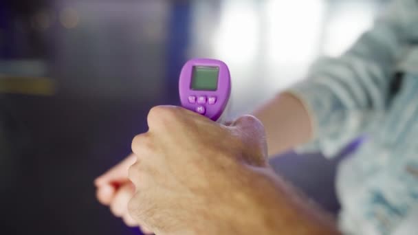 Vérification de la fièvre d'un visiteur avec un thermomètre numérique dans la région du poignet. Meida. Concept de protection contre l'épidémie de coronavirus, COVID 19 et les soins de santé. — Video