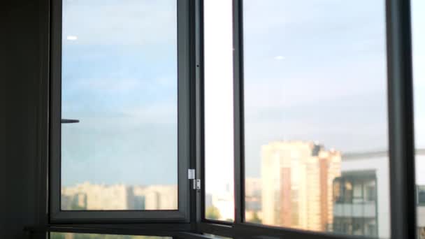 Schließen Sie das geöffnete Fenster mit dem blauen bewölkten Himmel und Hochhäusern draußen. Konzept. Leerer Balkon eines Wohnhauses am Morgen. — Stockvideo