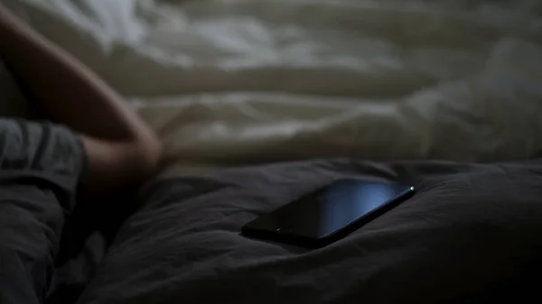 接近熟睡的男人和他的手机躺在床上。概念。一个晚上睡觉的家伙，他的智能手机就放在家里的毛毯上. — 图库照片