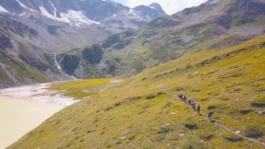 Dağlarda tatil yapan turistlerin en iyi manzarası. Şarjör. Bir grup turist dağlarda yürüyüşe gitti. Profesyonel rehber ve ekipmanlarla dağcılık turu