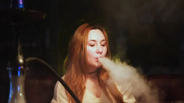 Porträt einer Frau, die in einem Aufenthaltsraum Wasserpfeife raucht und entspannt und sexy aussieht. Medien. Glamouröses Mädchen mit langen Haaren und natürlichem Make-up Shisha rauchen. — Stockfoto