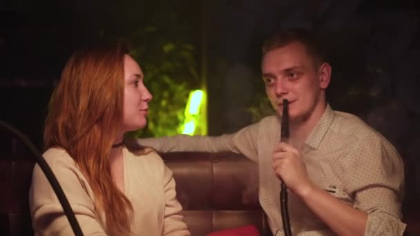 Muž mluví se svou přítelkyní s hadicí v baru. Média. Celebration, party concept, couple man with girl at shisha cafe lounge bar, date, love, relationship. — Stock video