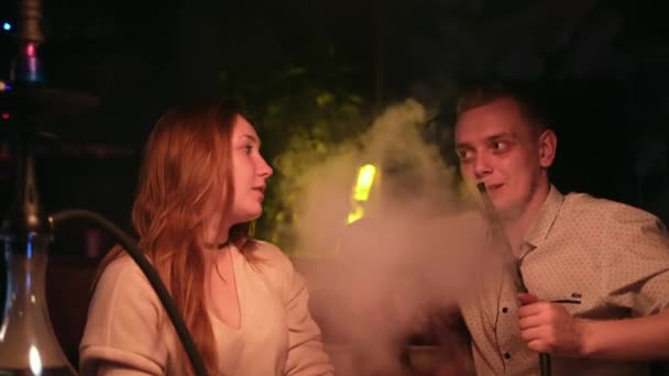 Roztomilý zamilovaný pár odpočívající na rande. Média. Kavkazský mladý muž a žena v černém kouření a hookah zatímco sedí u stolu v kavárně spolu. — Stock video