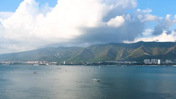 Fantastiskt naturlandskap med azurblå hav och skogsklädda kullar på blå molnig himmel bakgrund. Begreppet. Sommarbåtar seglar framför kuststaden. — Stockfoto