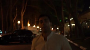 Gecenin geç saatlerinde sokakta koşan beyaz gömlekli bir adamın portresi. Medya. Genç işadamı arka planda parlayan sokak lambalarıyla gece geç saatlere kadar koştuğu için kaçıyor..