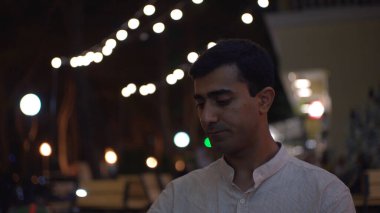 Cafe 'de buluşmadan önce telefonda konuşan bir adam. Medya. Çekici bir adam kahve içer ve akşamları sokak kafesinde sevgilisini bekler. Adam, kafede buluşmadan önce sevgilisiyle telefonda konuşuyor.