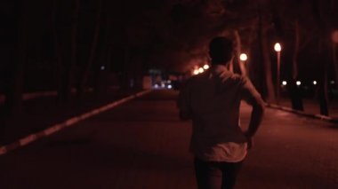 Geceleri şehirde koşan bir adam. Medya. Arka planda, şehrin arka planında tişörtlü bir adamın koşuşunun görüntüsü. Adam randevusuna geç kaldığı için geceleri şehirde koşuyor. Yoksa felaket olur.
