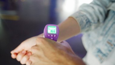 Bilek bölgesinde dijital termometresi olan bir ziyaretçinin ateşini kontrol ediyorum. Meida. Coronavirus, COVID 19 salgını ve sağlık hizmetlerinden korunma kavramı.