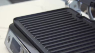 Yakın çekim elektrikli ızgara. Ev gereçleri. Arka bahçedeki barbekü için yeni elektrikli ızgaranın içinde teflon yüzeyi. Elektrikli ızgarada çizgileri olan siyah yüzey