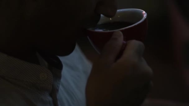 Primer plano del hombre bebiendo una taza de café por la noche. Concepto. Hombre caucásico bebiendo café en la oscuridad de la noche. Elegante hombre bebe café aromático fresco — Vídeos de Stock