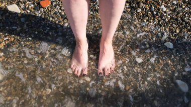 Sahildeki deniz dalgalı ayak manzarası. Kavram. Doğaya bağlı, güzel bacakları ve ayakları olan, tırnakları siyaha boyanmış, deniz ya da okyanus dalgalarıyla yıkanan bir kadın..
