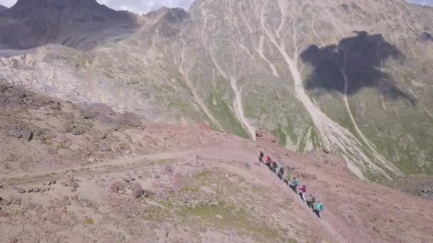 Légi felvétel a túrázó csapatról, ahogy egyenként másznak fel a hegyoldalon. Csípés. Utazás és sport életmód koncepció, turisták csoportja sétál a hegycsúcs felé. — Stock videók