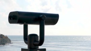 Halka açık plaj dürbünleri, arka planda okyanus bulunan madeni paralarla çalışıyor. Kavram. Turistik dürbün, nefes kesici görüntüler için optik araç.