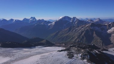 Mavi gökyüzü arka planında nefes kesen yüksek dağ manzarası. Şarjör. Güneşli bir günde, karlı zirveleri olan dev tepelerin üzerinde uçuyor..