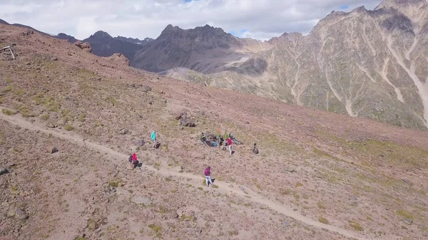 Blick von oben auf Touristen, die in den Bergen Urlaub machen. Clip. Eine Gruppe von Touristen wanderte in den Bergen. Bergsteigertour mit professionellem Führer und Ausrüstung — Stockfoto