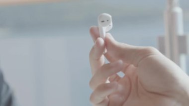 Kablosuz kulaklıkları yakın çekim. Hisse. Adam bir çift kablosuz kulaklığı uzatıyor. Modern Bluetooth kulaklıklar