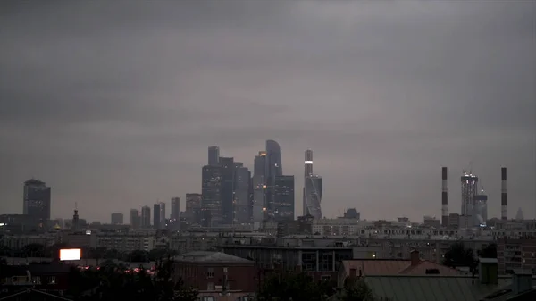 ロシアの夕方遅くにモスクワ市の高層ビル。行動だ。モスクワ中心部のビジネス地区、濃い灰色の雲と霧の下で近代的な建物のパノラマ. — ストック写真