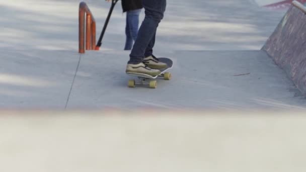 Achteraanzicht van een jonge man die skateboardt in een stadspark. De media. Man rijdt over het skateboard op een sportveld op een zonnige zomerdag. — Stockvideo