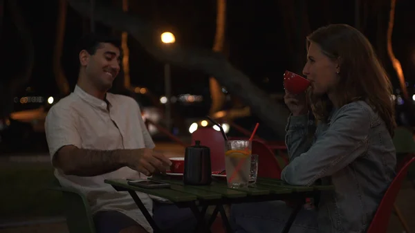 Genç aşık bir çift gecenin geç saatlerinde caddedeki kafede oturup sohbet ediyorlar. Medya. Güzel kadın ve erkek güney şehrinde çay içerler.. — Stok fotoğraf
