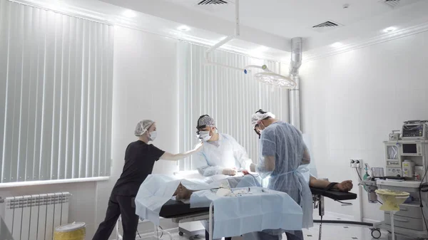 Gallbladder removal operation in the operation theatre. Action. Doctors helping patient during the surgery, bloody bandage is lying on the sterile table. — Stock Photo, Image