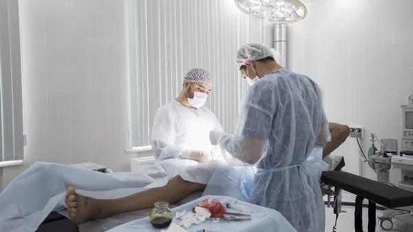 Process of surgery in the sterile operating room. Action. Two professional doctors performing real surgery with all the necessaey equipment, medical background. — Stock Photo, Image