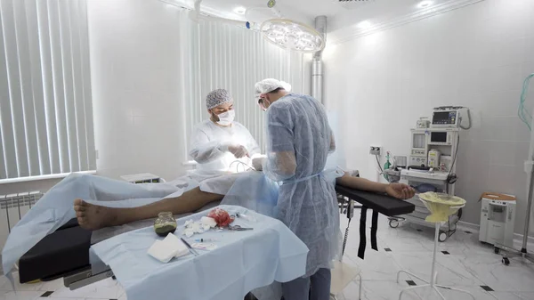 Process of surgery in the sterile operating room. Action. Two professional doctors performing real surgery with all the necessaey equipment, medical background with time lapse effect. — Stock Photo, Image