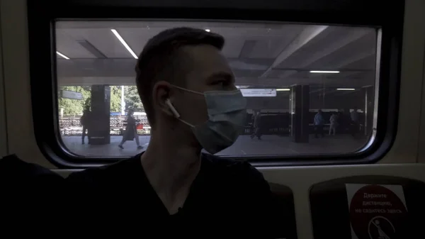 En man i en tunnelbanevagn med medicinsk mask. Börja. Botten bild av en manlig ansikte och de andra passagerarna i skyddsmasker, skydd mot virusinfektioner i kollektivtrafiken. — Stockfoto