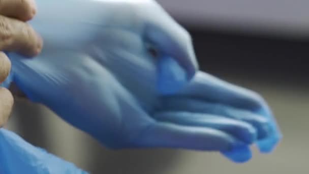Bulaşıcı hastalıklara karşı koruma, koronavirüs, enfeksiyonu önlemek için hijyenik eldiven giyen adam. Medya. Erkek eli yakın. Koruyucu mavi lateks eldiven giyiyor.. — Stok video