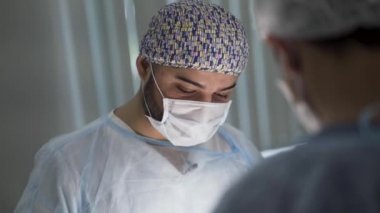 İşteki iki erkek cerrahı kapatın. Başla. Ameliyat sırasında steril maske takan ve üniforma giyen erkek doktorlar, tıp konsepti.