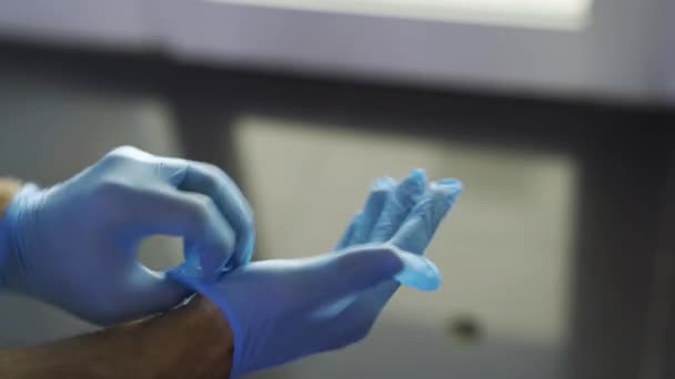 Ochrana proti nakažlivým nemocem, koronaviru, muži v hygienických rukavicích, aby se zabránilo infekci. Média. Detailní záběr muže ruce uvedení na ochranu modré latexové rukavice. — Stock video
