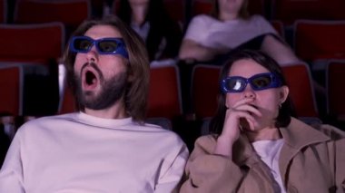 Üç boyutlu gözlüklerle korku filmi izleyen genç bir çift. Medya. Kadın ve erkek korku ve şok içinde film izlerken, boş zaman kavramı.