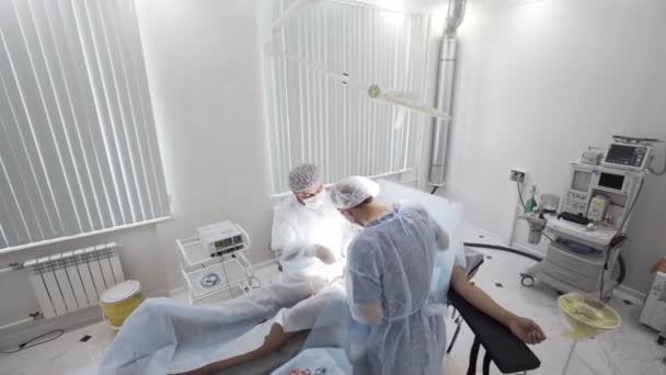 Gallbladder removal operation in the operation theatre. Action. Doctors helping patient during the surgery, bloody bandage is lying on the sterile table. — Stock Video