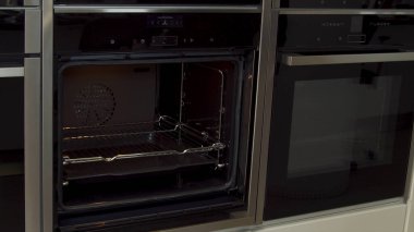 Mobilya atölyesindeki mutfak için yeni mini fırını açan adama yaklaş ve aç. Ev gereçleri. Yeni fırın modelinin sunumu, yüksek teknoloji konsepti.