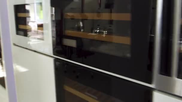 Κάμερα που κινείται κατά μήκος της σειράς των ψυγείων κρασιού και φούρνων στο κατάστημα οικιακών συσκευών. Οικιακά σκεύη. Νέες σύγχρονες μηχανές οικιακής χρήσης. — Αρχείο Βίντεο