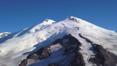 Avusturya Alplerinde kışın karlı ve buzlu dağ zirveleri. Şarjör. Mavi arkaplanda karlı bir kayanın havadan görünüşü..