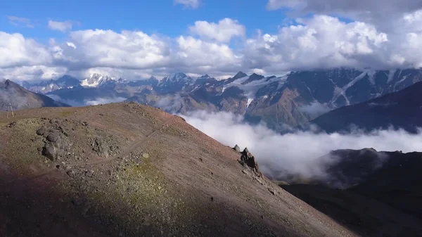 Mountain range in clouds on blue sky background. Clip. View from the mountain peak on amazing endless high hills and white flowing clouds, beauty of nature.