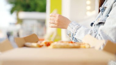 İtalyan yemeği, dışarıda mozzarella ile pizza yiyen bir kadın. Medya. Güneşli bir yaz gününde bir dilim pizza alan genç bir kadının elini kapatıyoruz..