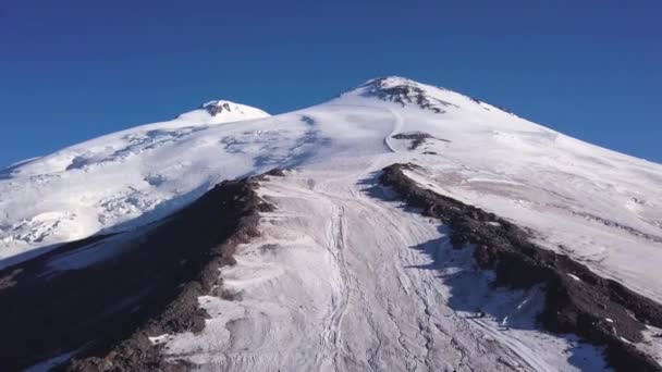 Snowy and icy mountain peaks of glaciers in Austrian Alps at winter. Clip. Aerial view of a snowy slope of a huge rock on blue sky background. — Stock Video