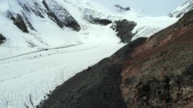 Kar ve kayalar bir buzulun eridiği dağ yamacını kaplıyor. Medya