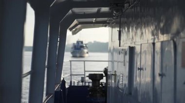 Endüstriyel kargo gemisi uzak arkaplanda görünen başka bir gemiyle nehir boyunca ilerliyor. Kırp