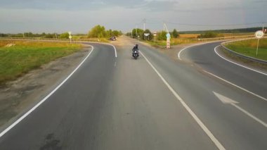 Boş bir asfalt otoyolda motosiklet kullanan evcil köpeği olan bir motosikletli. Kırp