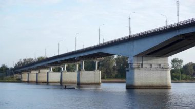 Güneşli bir günde büyük beton bir köprünün altında yüzen bir balıkçıyla şişme motorlu tekne. Kırp