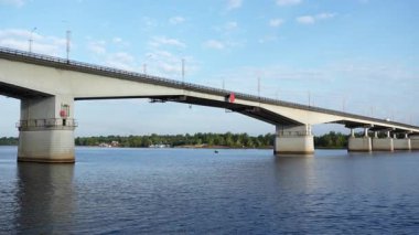 Şehir trafiği güneşli bir günde geniş bir nehri geçen büyük beton bir otoyol köprüsünde ilerliyor. Kırp