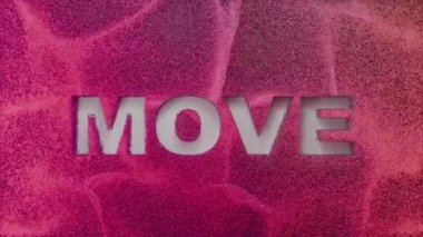 Yüzeyden kesilen kelimenin arkasında pembe ve mor simli parçacıklar kıvrılıyor.