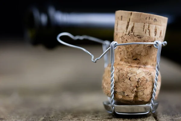 Cork from champagne on a wooden kitchen table. Good New Year\'s drinks and great fun. Dark background.