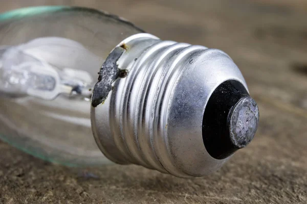 Tahta bir masanın üzerinde yatan ampul. Eski bağlamada aydınlatma aksesuarları. Koyu arka plan.