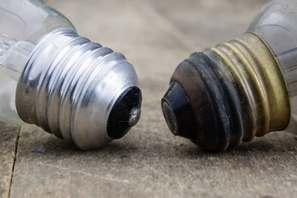 Tahta bir masanın üzerinde yatan ampul. Eski bağlamada aydınlatma aksesuarları. Koyu arka plan.