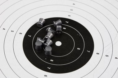 Ateş ve pnömatik silah. Tahta bir masada kurşun mermi ile kalkan ve hits. Karanlık arka plan.