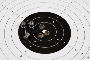 Ateş ve pnömatik silah. Tahta bir masada kurşun mermi ile kalkan ve hits. Karanlık arka plan.