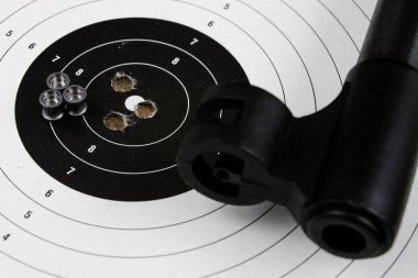 Ateş ve pnömatik silah. Tahta bir masada kurşun mermi ile kalkan ve hits. Karanlık arka plan.